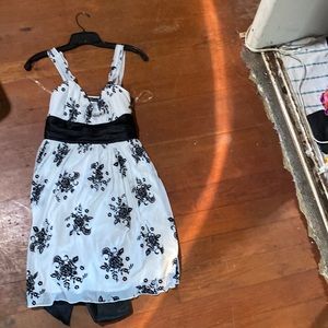 A white cocktail dress with a black floral print and black satin waist